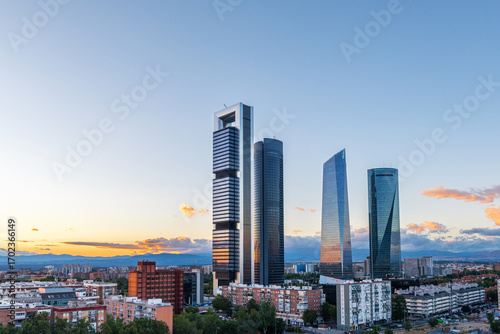 Cityscape of Madrid’s financial district at dusk, featuring modern skyscrapers illuminated against the fading evening sky.
