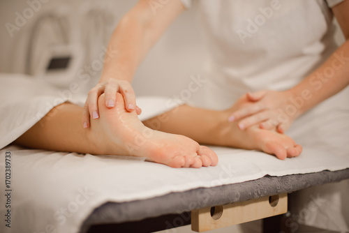 Professional woman hands doing foot massage on massage table in spa salon