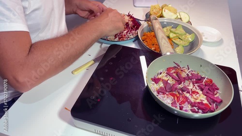 Add vegetables to a pan that is heated on a portable electric stove.