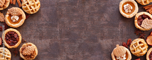 Fall pie theme dessert double border. Top down view against a dark stone banner background. Pumpkin, apple and pecan mini pies.