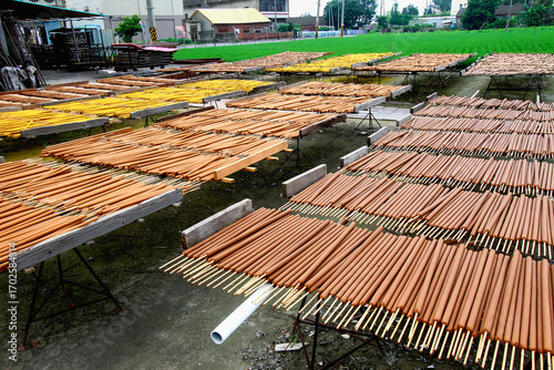 Rows of incense sticks dry under the sun on wooden racks. The outdoor setting highlights traditional handmade production. Xianxi Township, Taiwan.
