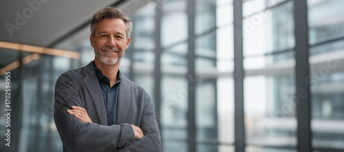 A confident mature man posing in a modern building setting with his arms crossed
