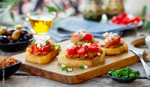 Bruschetta with olive tapenade and fresh tomatoes on cutting board. Wooden background. Close up.