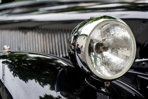 Close-up of shiny headlight on a black vintage car 