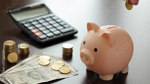 Close up view of man hands, calculator, piggy bank, indian rupee  coins (INR). Concept of saving money for retirement, cash settlement, financial goals, success, literacy and income planning in India.