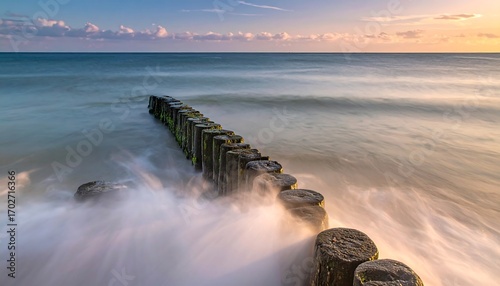 Calm sea waves crashing against a breakwater at sunset