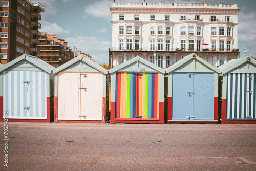 Colorful beach huts lined up along the promenade in Brighton during a sunny day