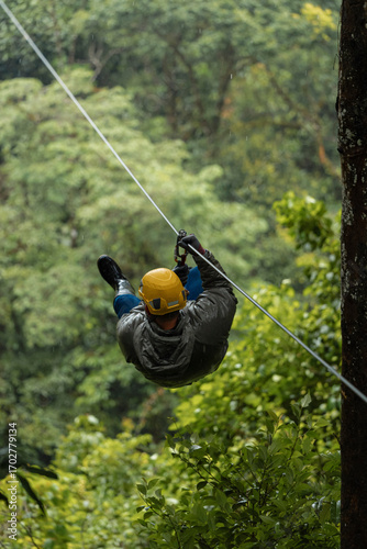Person ziplining through tropical forest on a rainy day