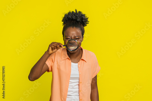 Foto African American woman holds magnifying glass distorting her smile, creating comical effect