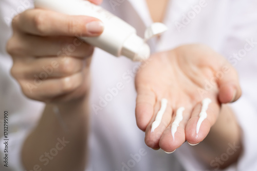 A person applying the correct amount of sunscreen for face and neck (three finger lengths).