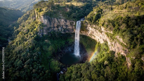 Majestic Waterfall Cascading into Lush Green Valley with Rainbow