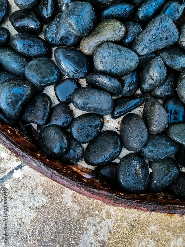 Wet black pebbles with water droplets, close-up top view