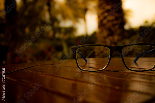 Stylish eyeglasses on a wooden table with warm light, suitable for business, vision care, or lifestyle marketing
