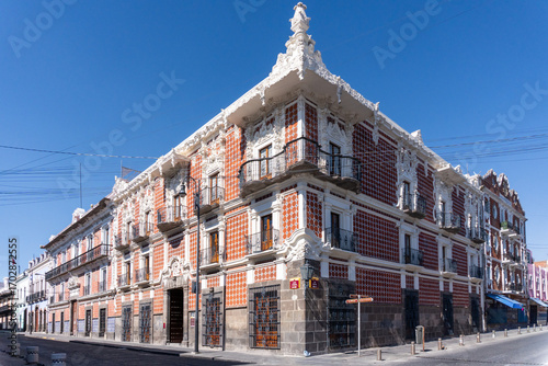 A large building with a white facade and red trim. The building has a balcony on the second floor. City of Puebla, Mexico, crafts