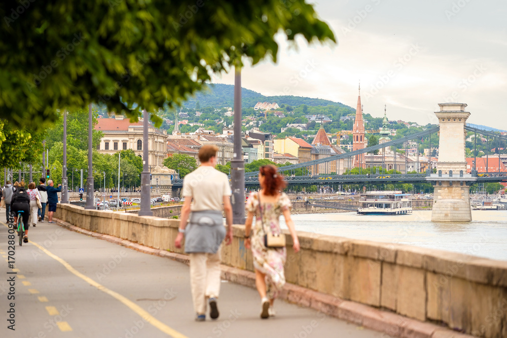 Naklejka premium Riverside promenade in old city, young couple walking
