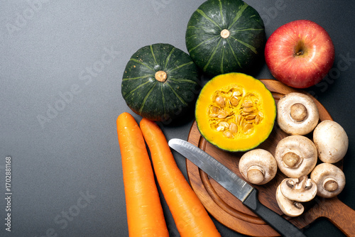 Fresh vegetables and fruits with pumpkin carrot apple and mushrooms on dark background