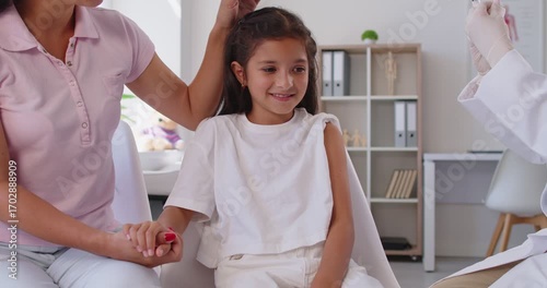 Doctor gives an injection to a child as a mother holds her hand, supporting vaccination and immunization in a healthcare setting for protection and smile. Child gets vaccine shot in medical clinic.
