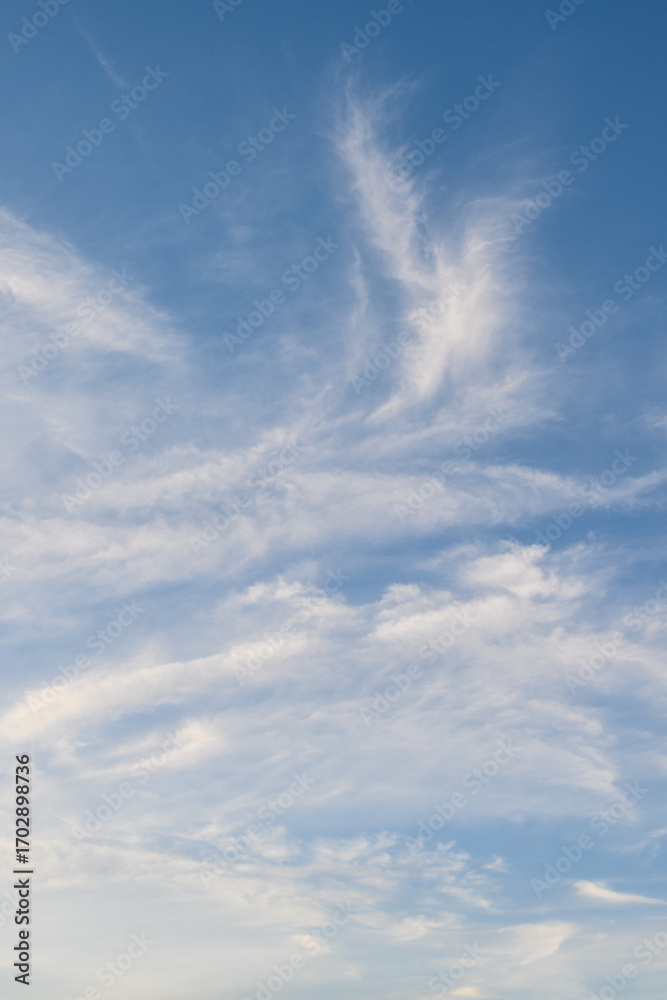 Fototapeta premium Sunset sky background, blue sky with hint of yellow and white wispy clouds