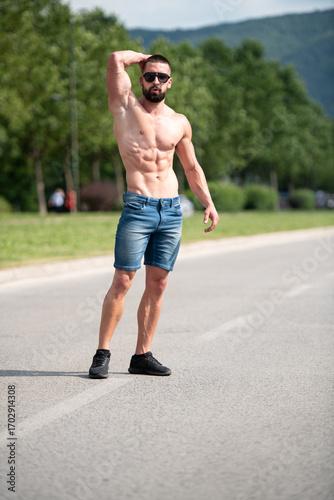 Schilderij op canvas Model Flexing Muscles Outdoors