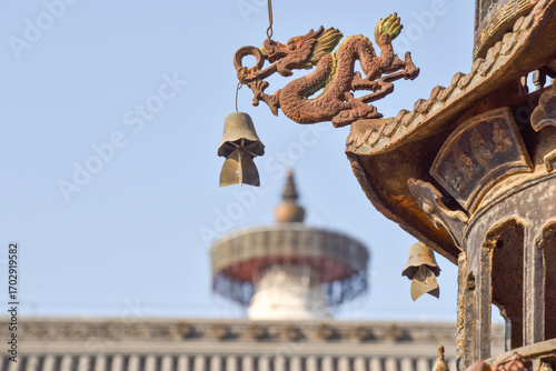 Traditional Dragon Bell Hanging from Temple Roof with Stupa in Background