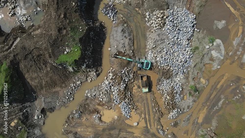 Excavator and dump truck working in rock and sand quarry, Construction and mining site view from above.