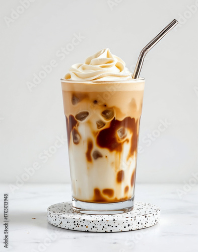 Iced dalgona coffee latte with whipped cream foam in tall glass with straw refreshing cold beverage cafe style drink