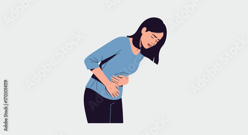 Woman clutching stomach in pain wearing blue shirt and dark pants on a light grey background