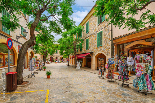 A picturesque street of shops and cafes in the medieval village of Valldemossa, Spain, on the Mediterranean Balearic island of Mallorca.	