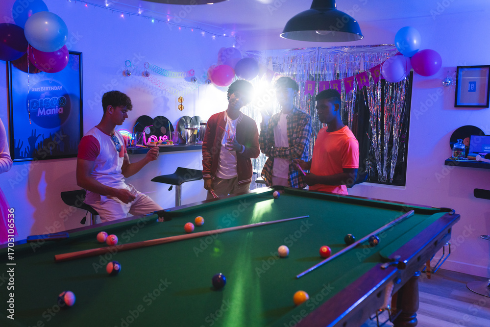 Naklejka premium Celebrating birthday, teenagers playing pool in festive room with balloons and decorations