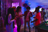 Teenagers celebrating with glow sticks and dancing at lively indoor party