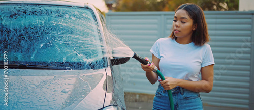 Car Wash Ritual: A young woman diligently cleans her car. Sprays water with focused intensity, highlighting the blend of everyday routine and personal pride.
