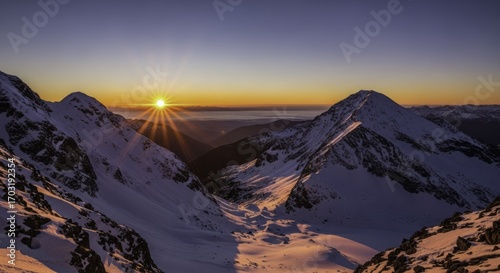 Majestic Sunrise Over Snow-Capped Mountains with Golden Sun Rays and Vibrant Alpenglow on Icy Peaks, Illuminating a Serene Winter Wonderland