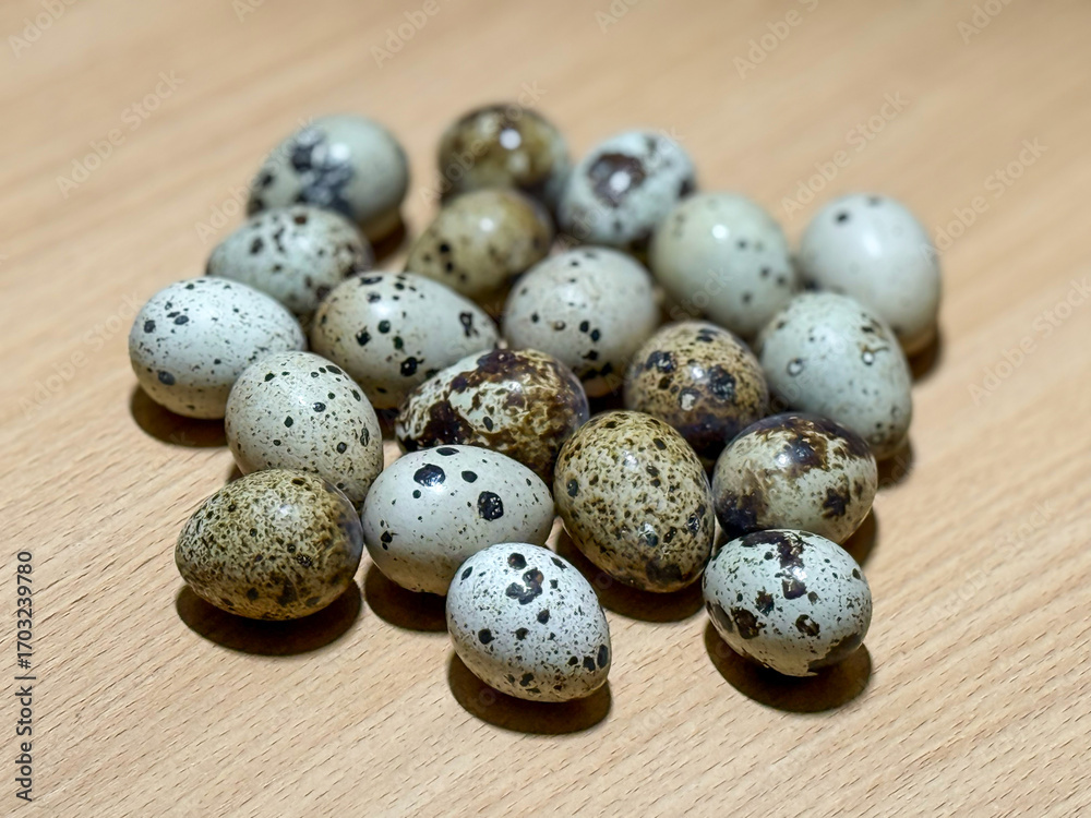 Obraz premium Fresh quail eggs in a wooden table close-up. Fresh quail eggs on a brown wooden table. Raw quail eggs close-up on a culinary background. Concept of preparation for cooking, healthy eating. 
