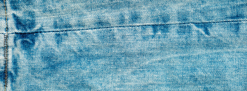 A close-up of blue denim fabric highlights its worn texture and stitching details. The light enhances the faded color