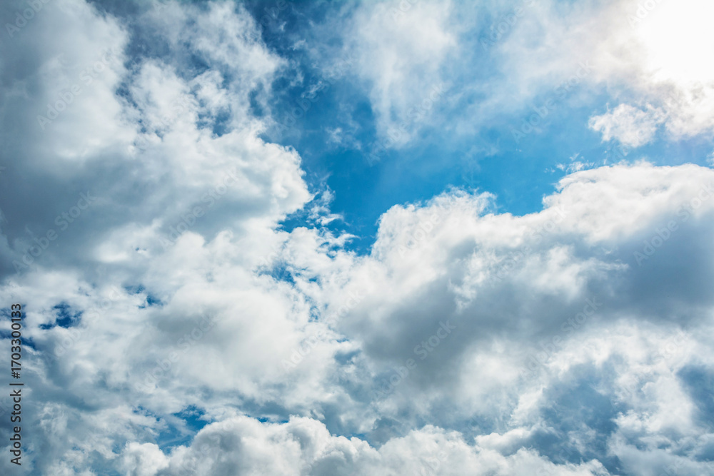 Fototapeta premium White fluffy clouds scattered across a deep blue sky creating a bright and airy weather background with natural light