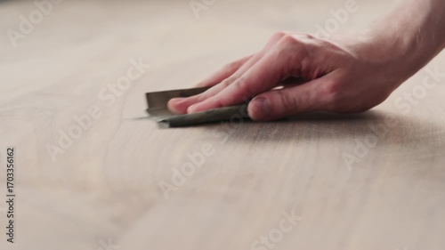 Slow motion slide orbit shot of man hand sanding black walnut wood table
