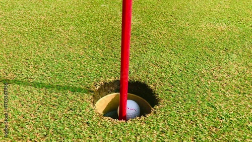 Perfect Golf Putt Ball Rolling into the Hole. Close-up of golf ball smoothly rolling on green and sinking into the hole with precision.