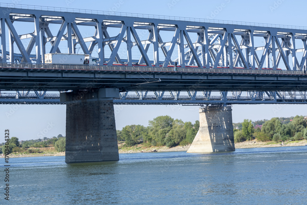 Fototapeta premium Large steel truss railway bridge crossing a wide river under a clear blue sky