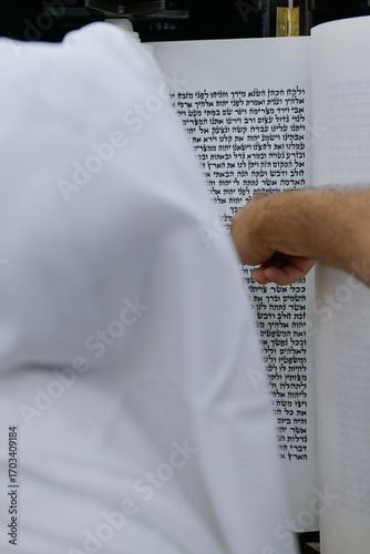 A bar mitzvah boy reading from the Torah scroll in a synagogue.