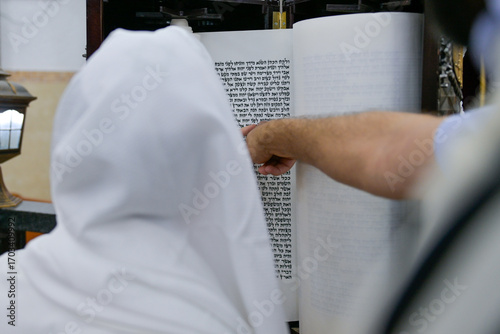 A bar mitzvah boy reading from the Torah scroll in a synagogue.