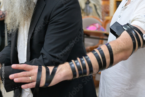 Father puts on tefillin at son's bar mitzvah in synagogue