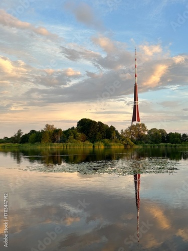 Riga Radio and TV Tower reflecting in the water of the Daugava river with a cloudy sky, Latvia, June 2024
