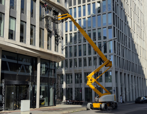 Cleaner worker using a cherry picker to clean a glas facade of a contemporary office building