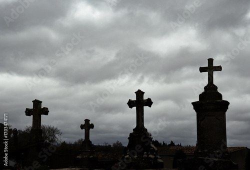 Medieval stone crosses from an ancient cemetery silhouetted against a dramatic cloudy sky at sunrise.