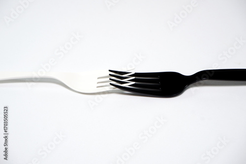 Black and white forks combined together on white background close-up view 