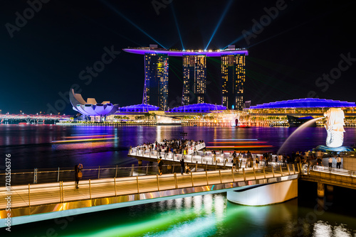 Canvas Print Singapore Marina Bay at night with Marina Bay Sands and Merlion Park illuminated, attracting crowds of visitors, symbolizing tourism economy and vibrant city life