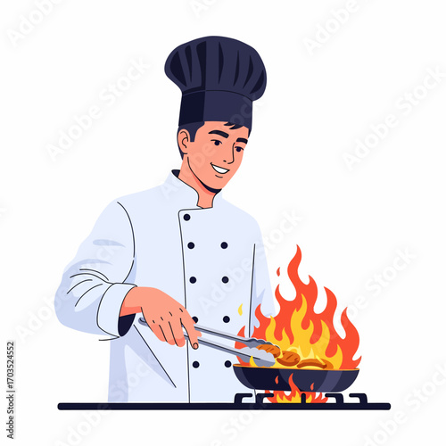 A smiling male chef in a professional uniform and hat is cooking food with tongs in a flaming pan on a stove.