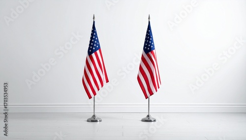 Two upright American flags on poles with gold finials against white wall
