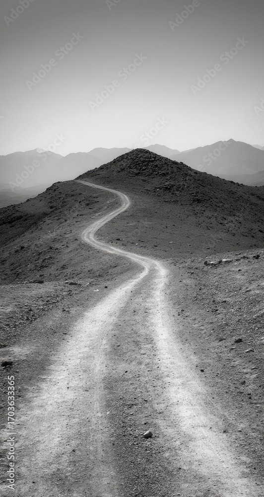 Fototapeta premium A winding dirt road ascends a barren hilltop under a pale sky