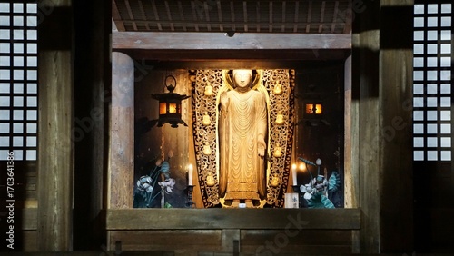 Night view of a Japanese temple entry with lit statue of buddha in the background